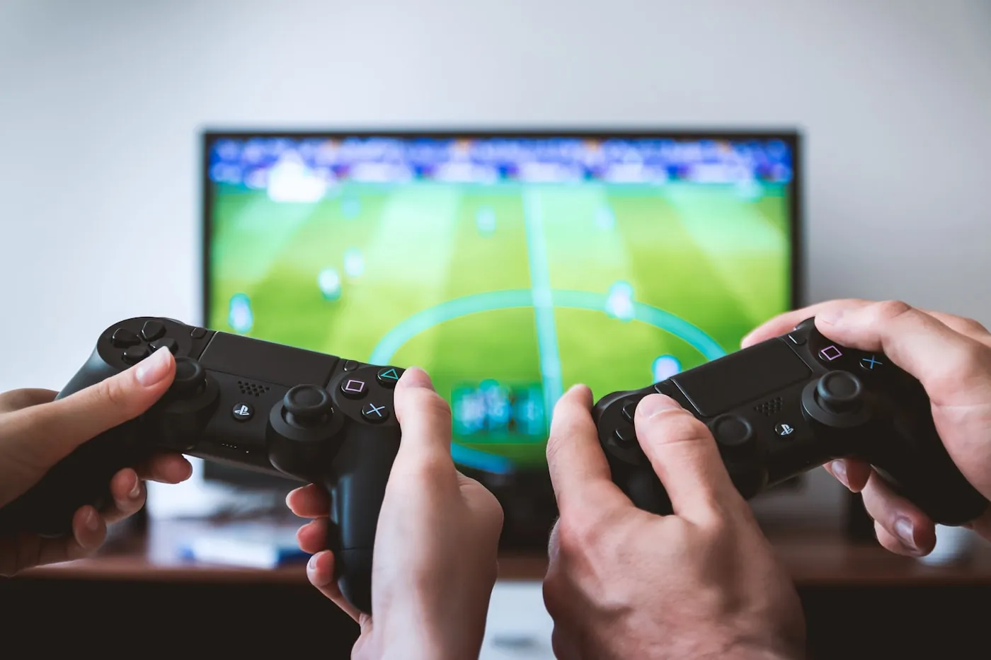 Two players sharing controllers on a couch, screen glowing in front of them